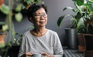 Mature person drinking tea on their balcony